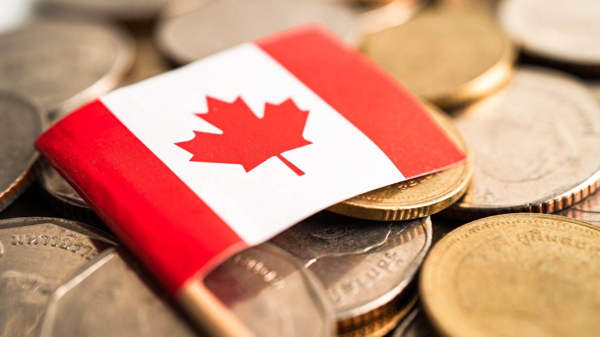 A Canadian flag resting on a stack of gold and silver coins