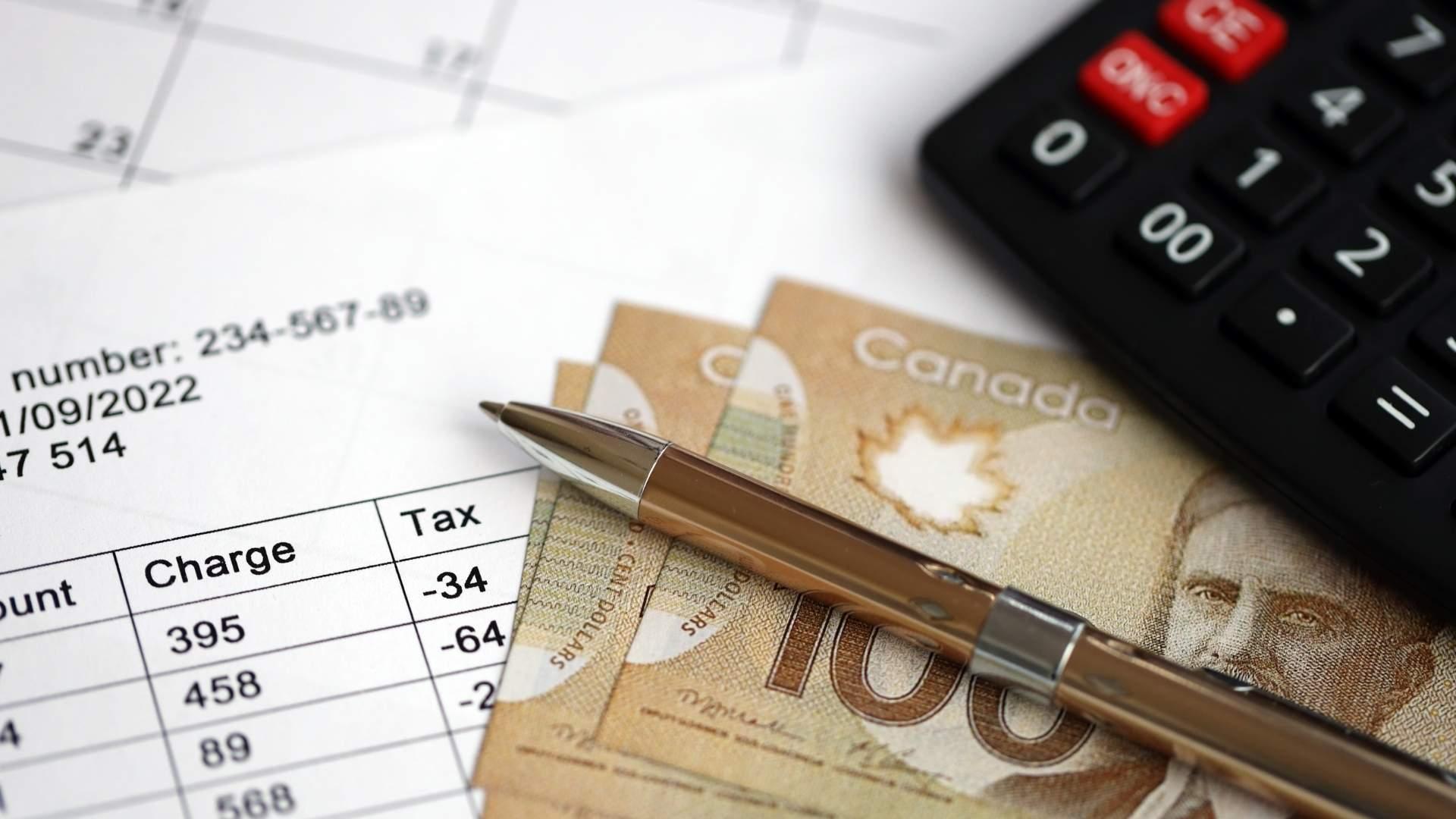 Canadian banknotes with a pen, calculator, and transaction document