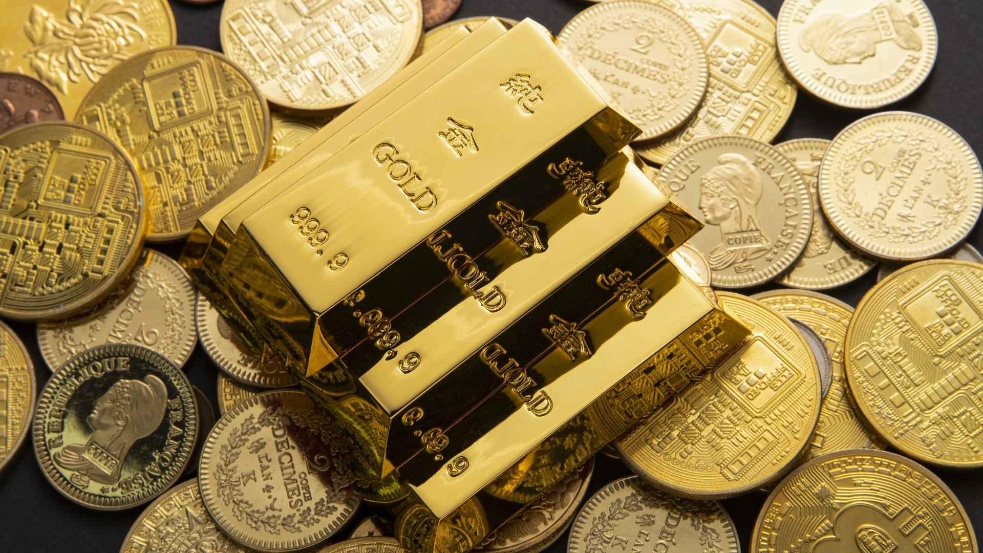 Stacked physical gold bars resting on gold coins